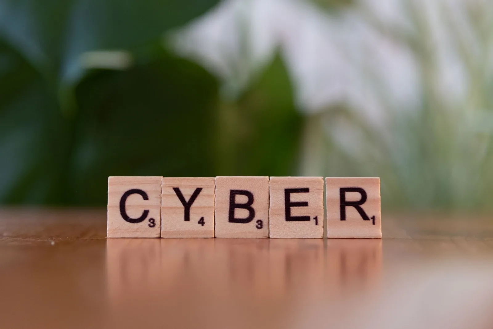 Wooden letter tiles spelling 'CYBER' on a blurred background, representing cybersecurity.