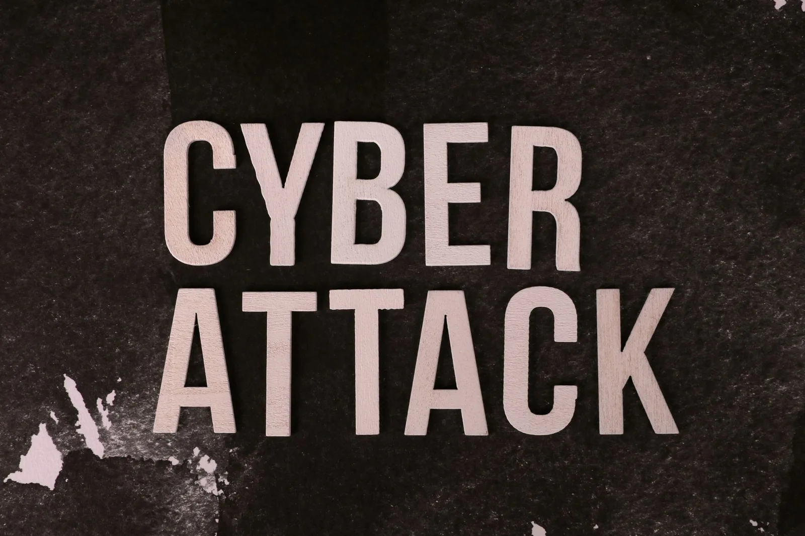 Text 'Cyber Attack' on textured dark paper highlights digital security threat concept.