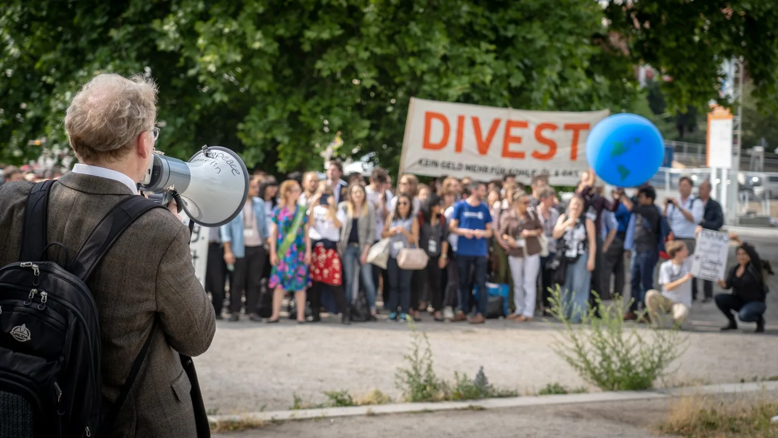 Protesters gather in Berlin, Germany, advocating for divestment and environmental action.